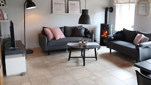 Un salon moderne comprenant un canapé, deux fauteuils, une table basse et une cheminée.
