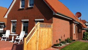 Une maison en briques rouges, avec un toit en pente, une porte en bois et une antenne parabolique.
