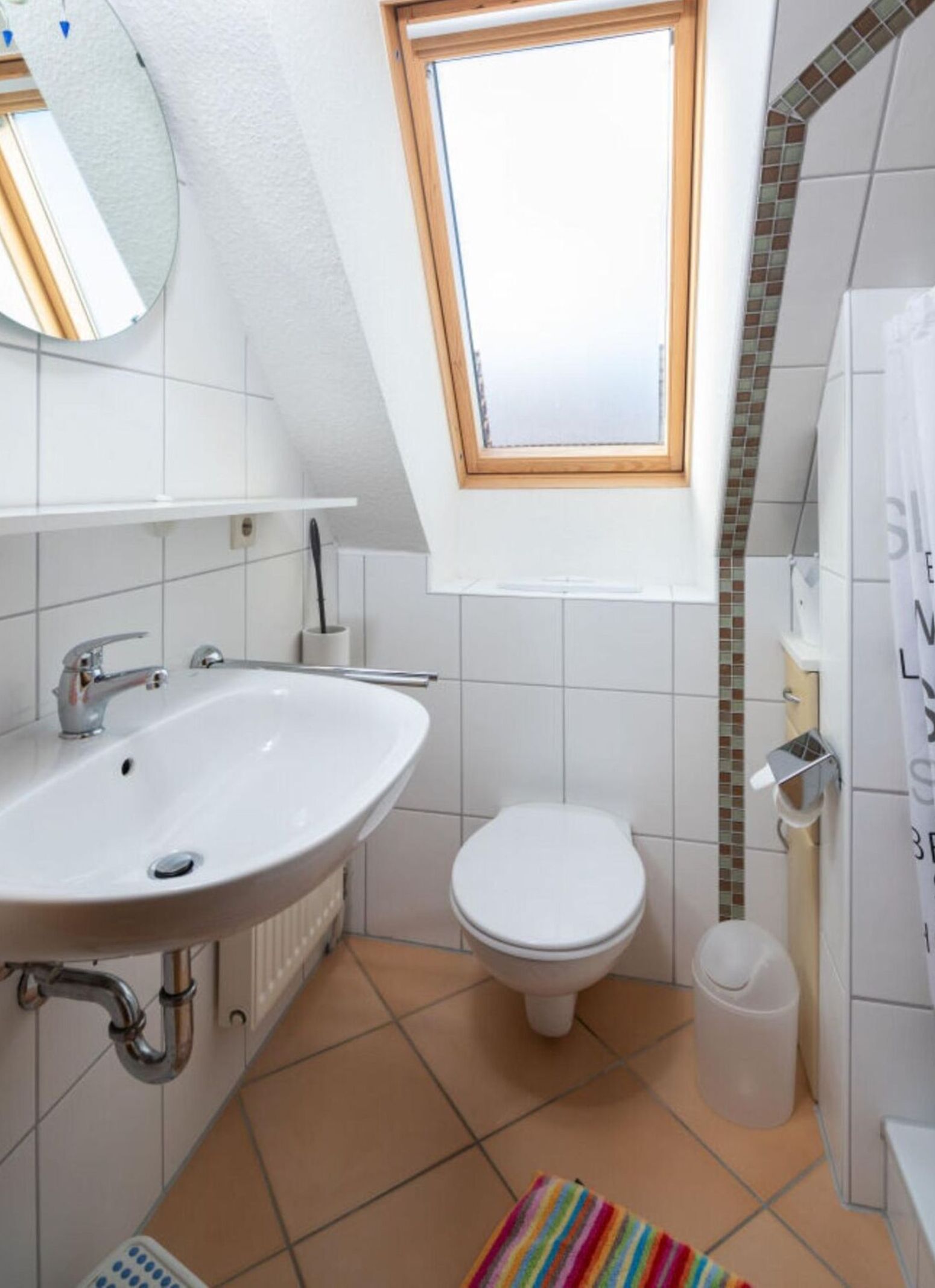 A bathroom with a white sink, a toilet, and a window above the toilet.