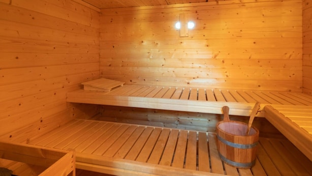 Un sauna en bois avec des bancs et un seau en bois.