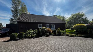 A house with a tiled roof, a driveway, and well-maintained landscaping. - Ferienhaus mit Blick in die Weite Wiesenlandschaft 5 Min.vom Natursee Entfernt (Hage)
