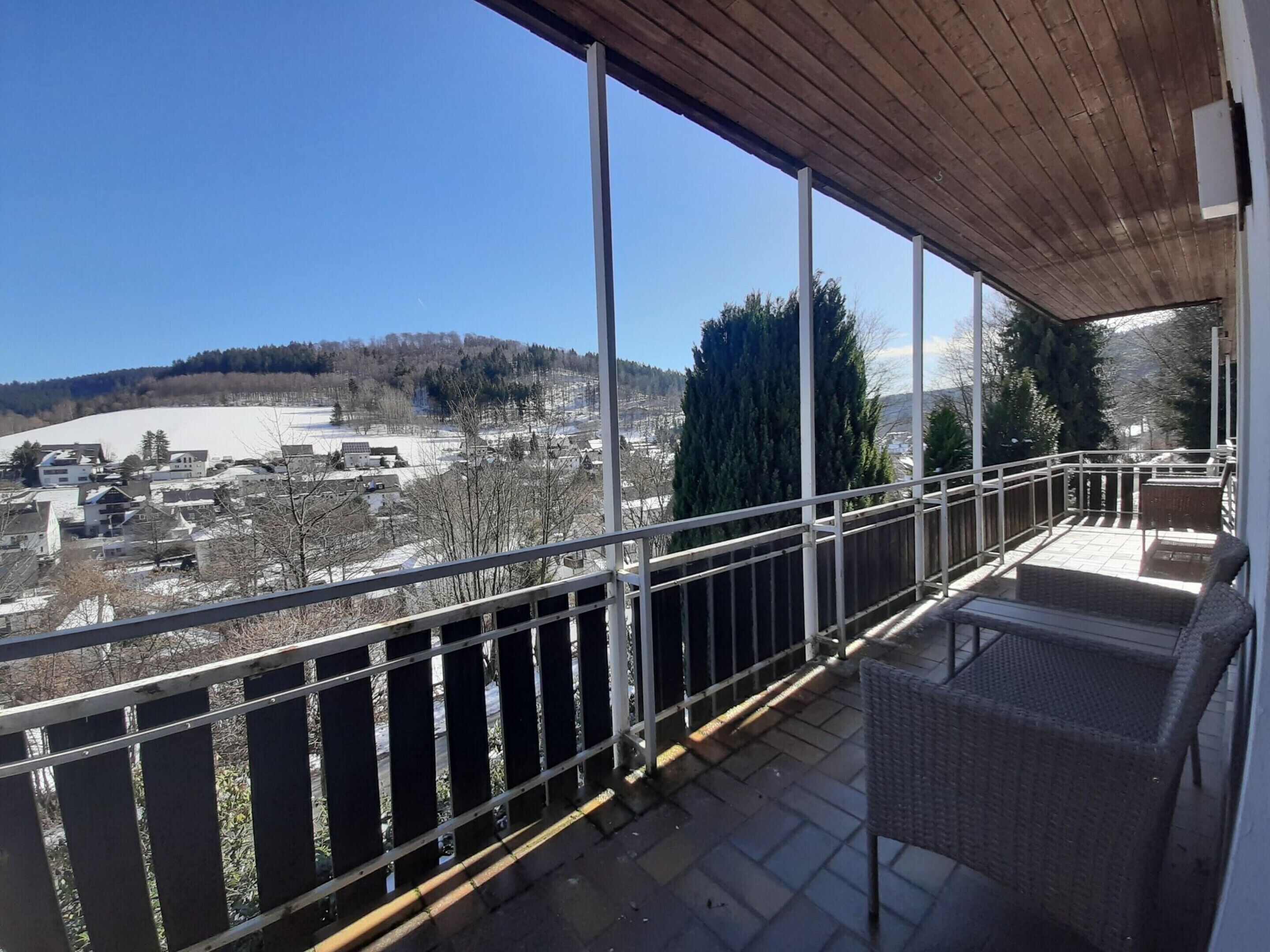 A balcony with a view of a snowy landscape and buildings.