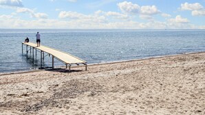Eine Mole, die sich in ruhiges Wasser erstreckt, mit blauem Himmel darüber.