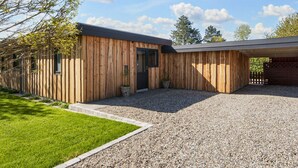 A modern wooden building with a gravel driveway and a grassy lawn. - 5 Person Holiday Home in Sydals (Sydals)