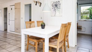 A dining area with a white table and wooden chairs, a white refrigerator, and a window with a view of greenery. - 5 Person Holiday Home in Sydals (Sydals)
