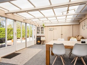 A modern kitchen with a built-in stove, a dining table with chairs, and a large window overlooking a garden. - 5 Person Holiday Home in Sydals (Sydals)