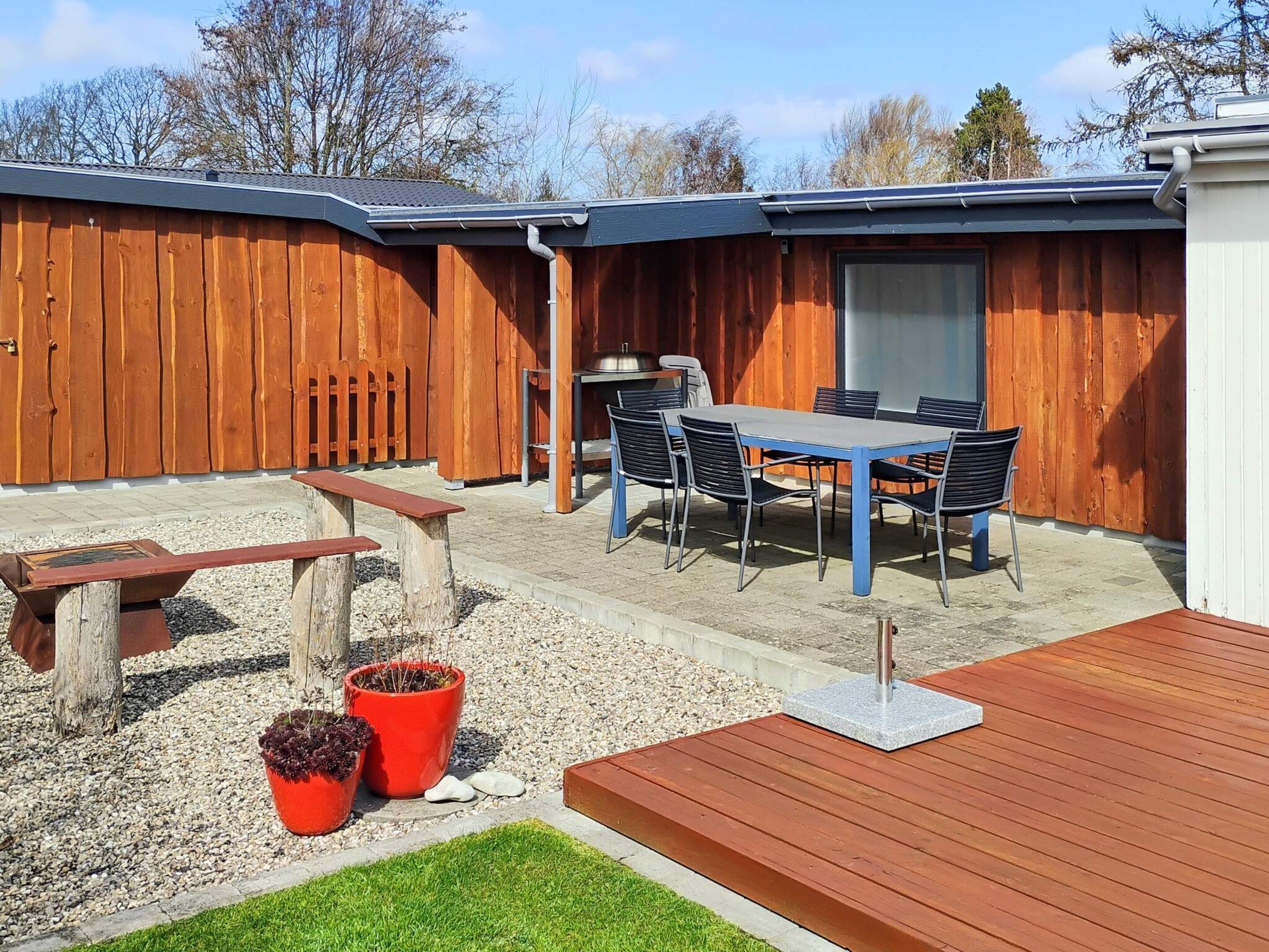 Eine Terrasse mit Tisch und Stühlen, einem Grill und einem Holzdeck.