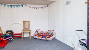 A room with a wooden ceiling, a polka-dotted ball pit, a wooden chair, and a red toy car. - 5 Person Holiday Home in Sydals (Sydals)