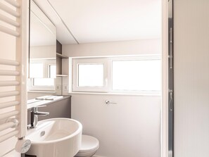 A compact bathroom with a white sink, a mirror, and a toilet.