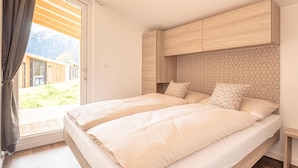 A bedroom with a bed, a window with curtains, and a view of the outdoors. - Modern Chalet With air Conditioning (Kotschach-Mauthen)