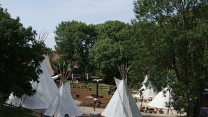 A campground with several white tents and a wooden fence. - Seepark Burhave Haus 8 (Butjadingen)