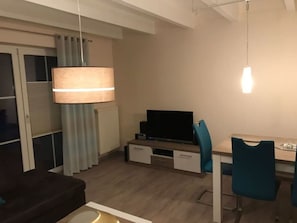 A modern living room with a sofa, a TV, a desk, and chairs. - Seepark Burhave Haus 8 (Butjadingen)