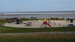 A beach with play structures, a slide, and a sandy area with umbrellas. - Seepark Burhave Haus 8 (Butjadingen)