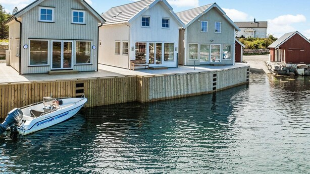 En fastighet vid vattnet med tre moderna hus som är sammanlänkade med en träbrygga.