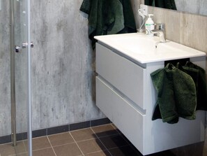 A bathroom with a white sink, a mirror, and a glass shower door.