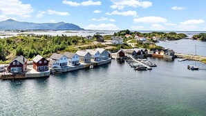 En kustby med hus som står på pålar över vattnet, en brygga och båtar.