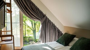 A bedroom with a bed, a desk, and a view of greenery outside. - Spacious Holiday Home With Garden (Wekerom)