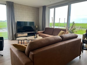 A modern living room with a leather sofa, a flat-screen TV, and a coffee table.