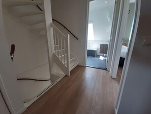 A staircase leading to a bedroom with a large window, a bathroom with a bathtub, and a wooden floor.