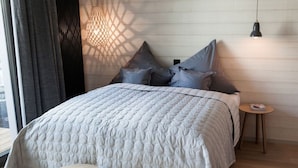 A bedroom with a large bed, a small round table, and a hanging light fixture. - 6 in het Huis Meerloft (Norderney)