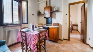 Une cuisine compacte comprenant une table à manger pour deux personnes, une cuisinière et un petit placard.