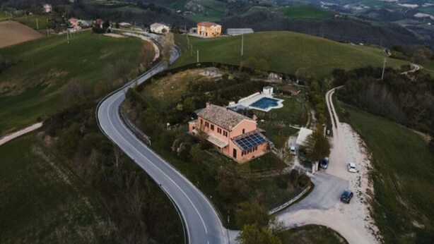 Une maison de campagne avec une allée sinueuse, une piscine et un panneau solaire.