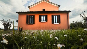 Une maison à la façade simple, de couleur orange, avec des volets noirs et un toit plat.