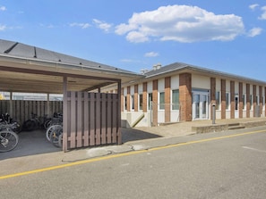 A building with a covered parking area and a brick facade. - Apartment With Terrace in a Holiday Park (Fano)