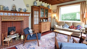 Una sala de estar acogedora con chimenea de ladrillo, mobiliario de madera y un ventanal con vista a la vegetación.