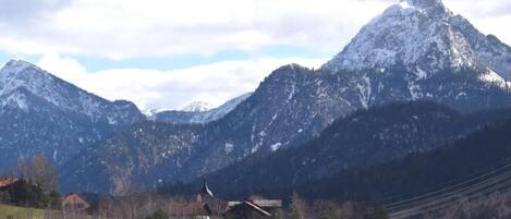 Un paysage de montagne avec un lac au premier plan et une église avec un clocher au milieu.