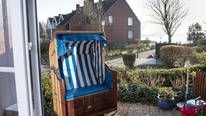 A wicker chair with a striped cushion in a garden area. - Small Sundblick by the sea in Lemkenhafen (Fehmarn)