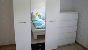 A white wardrobe with multiple drawers and a mirrored closet door. - Muller Comfortable Holiday Residence (Lutzkampen)