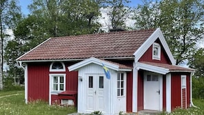 Una casa roja y blanca con techo de tejas, un pequeño porche y una bandera en la puerta.