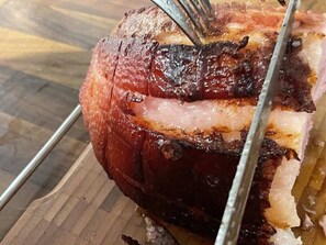 A roasted ham with a fork inserted, placed on a wooden surface. - Holiday Home Hus Rusken (Stockaryd)