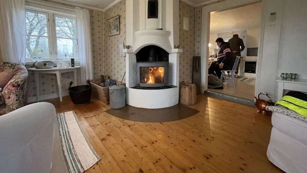 Una sala de estar acogedora con chimenea, suelo de madera y vistas al exterior.