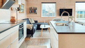 A modern kitchen with a built-in oven, a dining area with a small table and chairs, and a large window providing natural light. - 6 Person Holiday Home in Karrebaeksminde (Karrebæksminde)
