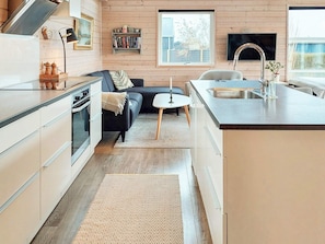 A modern kitchen with a built-in oven, a dining area with a small table and chairs, and a large window providing natural light. - 6 Person Holiday Home in Karrebaeksminde (Karrebæksminde)