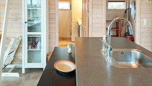 A modern kitchen with a stainless steel sink, a dark countertop, and a glass cabinet with decorative items. - 6 Person Holiday Home in Karrebaeksminde (Karrebæksminde)