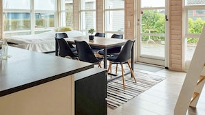 A modern kitchen with a central island, dining table with chairs, large windows, and a view of the outdoors. - 6 Person Holiday Home in Karrebaeksminde (Karrebæksminde)