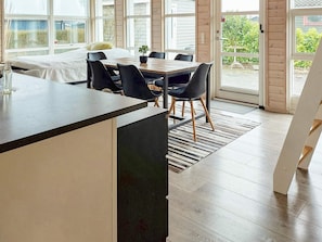 A modern kitchen with a central island, dining table with chairs, large windows, and a view of the outdoors. - 6 Person Holiday Home in Karrebaeksminde (Karrebæksminde)