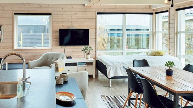 A modern, well-lit room with a large bed, a dining table, and a TV mounted on the wall. - 6 Person Holiday Home in Karrebaeksminde (Karrebæksminde)