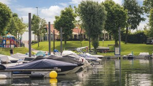 Uma marina com barcos atracados, um parquinho infantil e uma área gramada com árvores.
