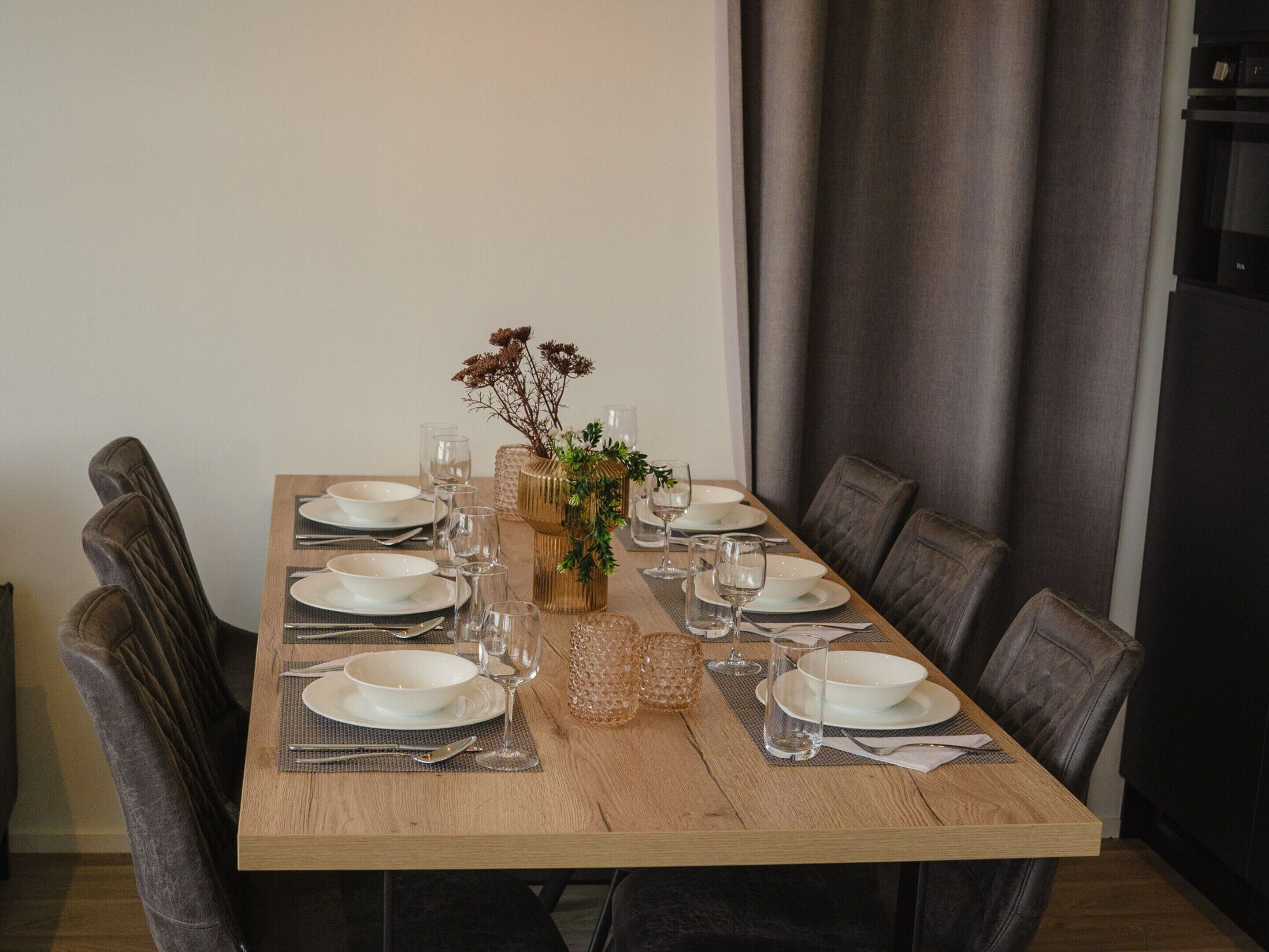 Een eettafel gedekt voor zes personen, met borden, glazen en bestek.
