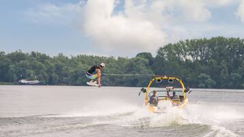 A wakeboarding event with a wakeboarder performing a jump and a boat towing them.