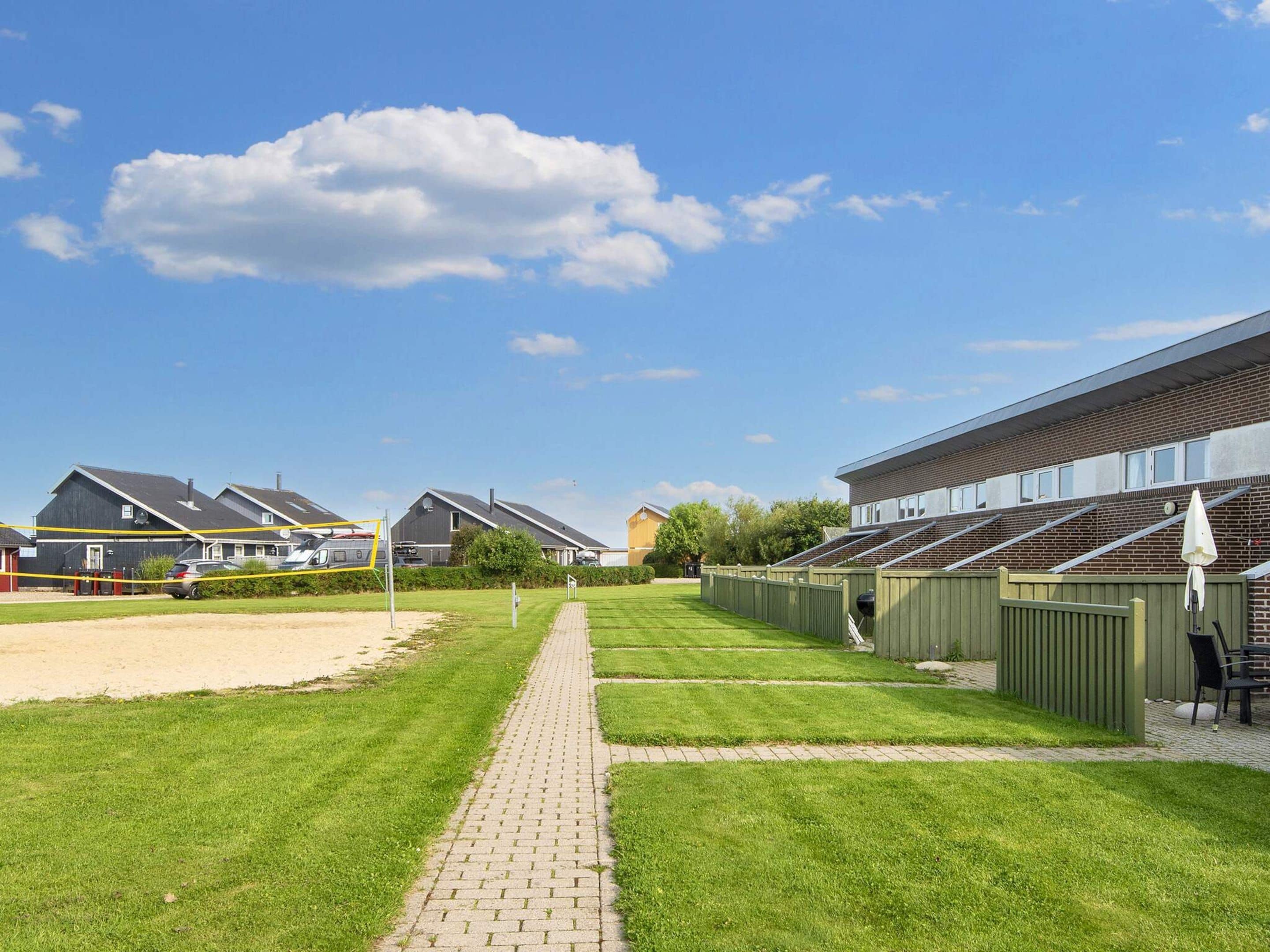 Une rangée de maisons modernes, avec un chemin pavé menant à une zone herbeuse.