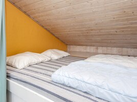 Una habitación pequeña con cama individual, techo inclinado y paneles de madera.