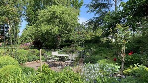 Un jardin agrémenté d’une table et de chaises, entouré de différentes plantes et fleurs.
