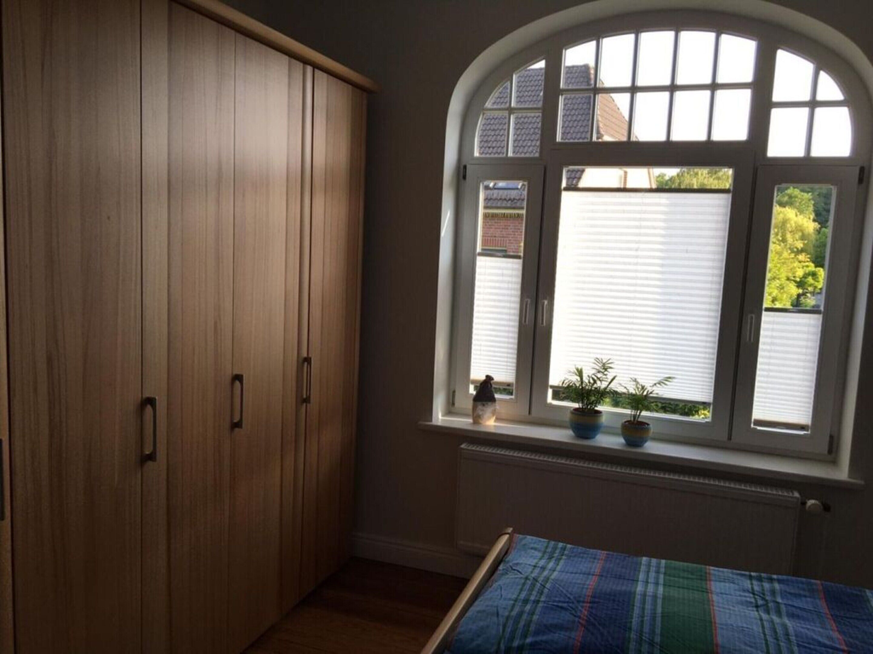 Un dormitorio con cama, armario y ventana con persianas.