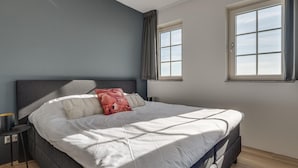 A modern bedroom with a large bed, two windows, and a nightstand. - Cozy Holiday Home in a Holiday Park in Zeeland (Ossenisse)