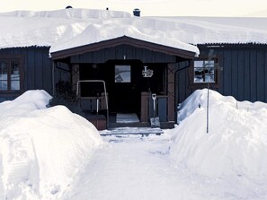 A wooden building with a snow-covered entrance, a sign above the door, and a window on the right side. - 5 Person Holiday Home in Idre (Idre)